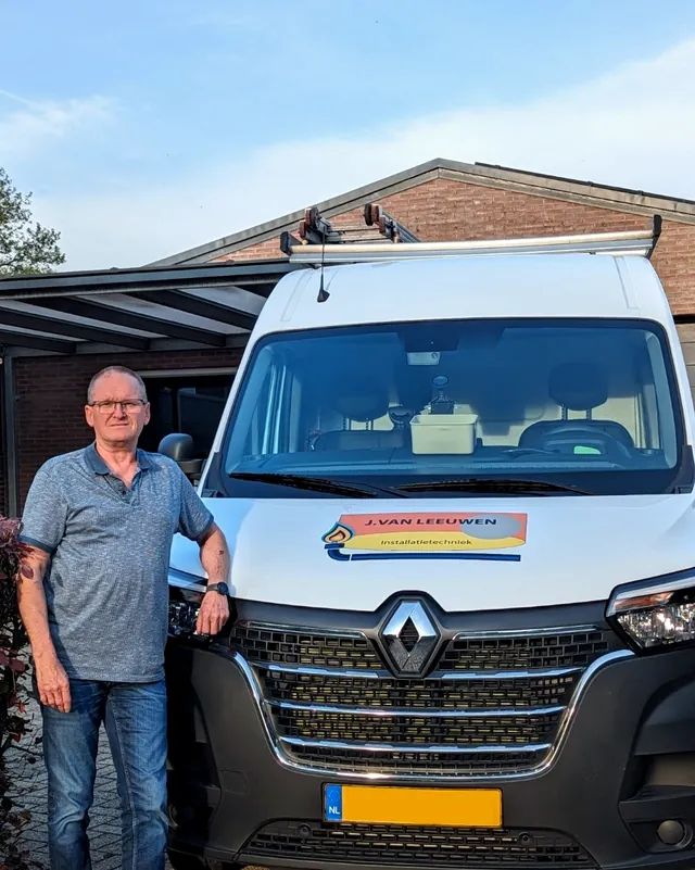 Een man in poloshirt staat naast de witte bedrijfsbus van J. van Leeuwen Installatietechniek
